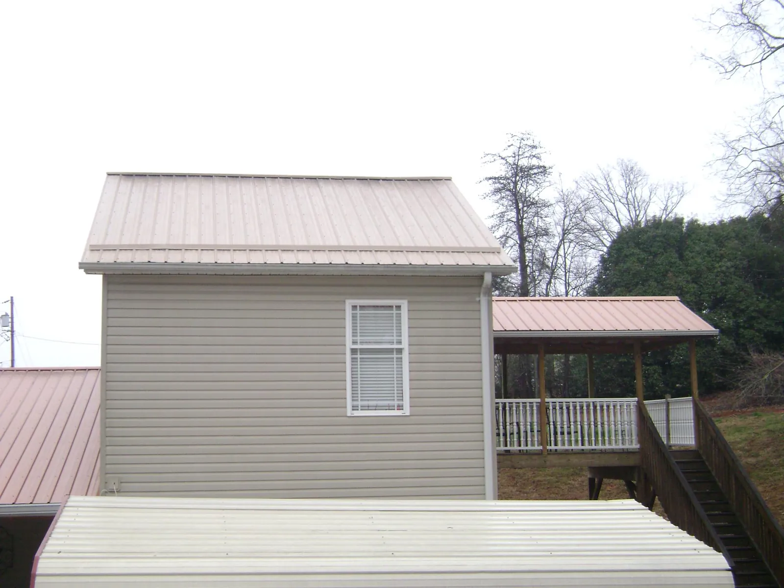 Tan metal roofs on a two story addition and attached porch, from a Roof Replacement job in Manning